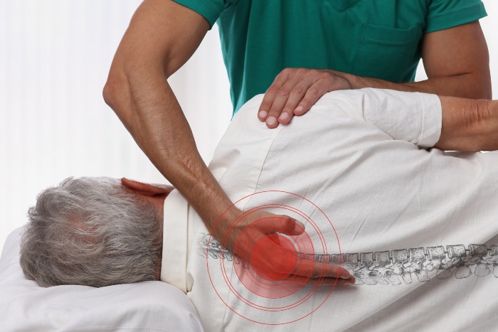 a chiropractor helping an aged patient with backpain, Pikesville, MD