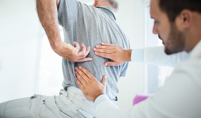 Doctor helping an aged patient with lower backpain, Pikesville, MD